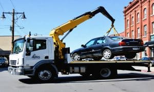 خودروی جرثقیل دار در حال بلند کردن یک خودروی سواری با جرثقیل و حمل آن